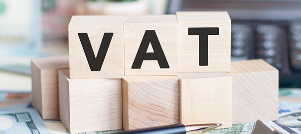 VAT concept with wooden blocks and coins on table, business concept