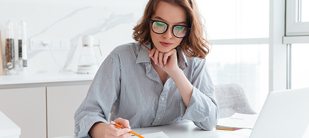 Young concentrated businesswoman in glasses and striped shirt wo